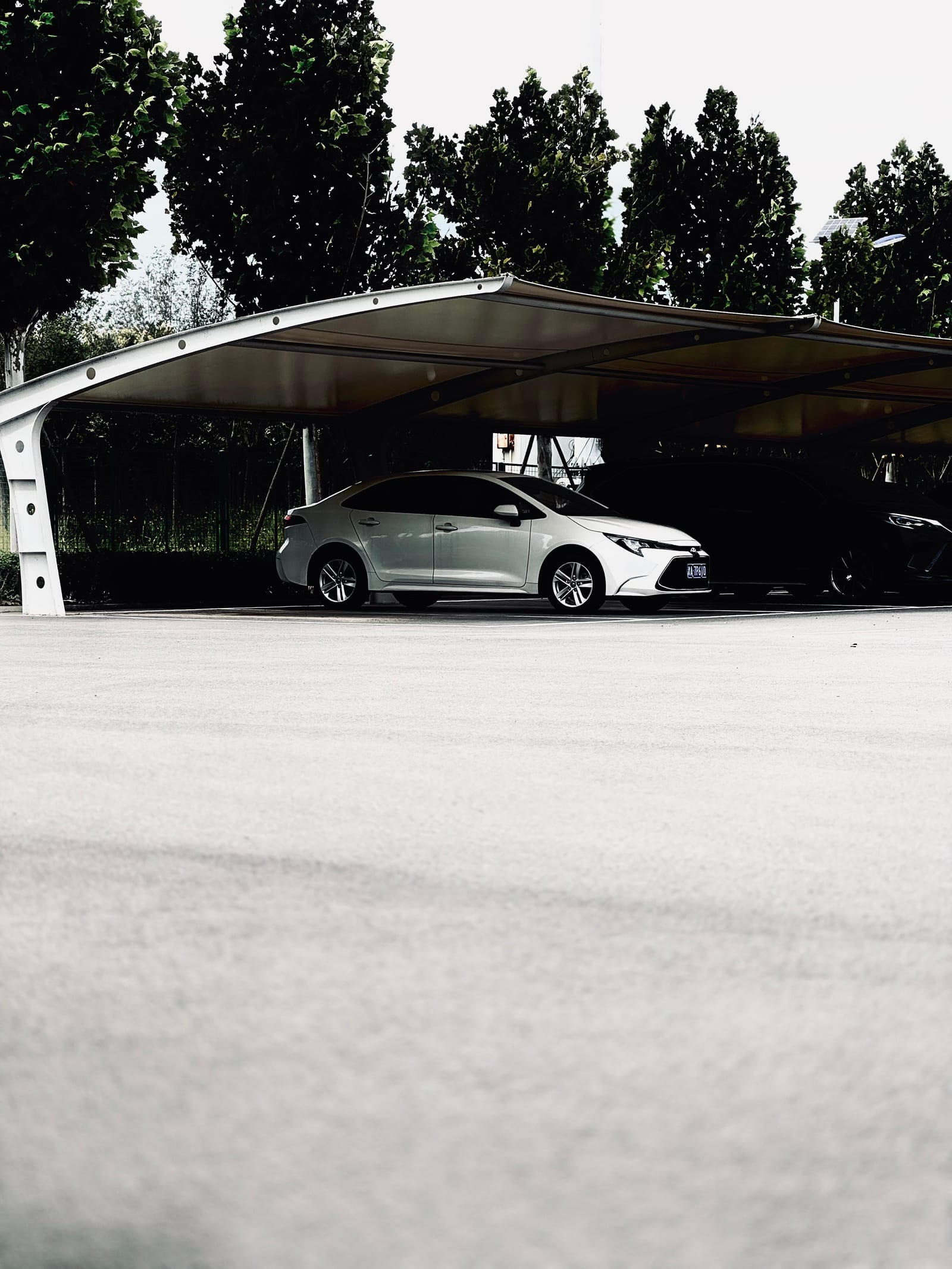 A modern car parked under a sleek metal canopy carport