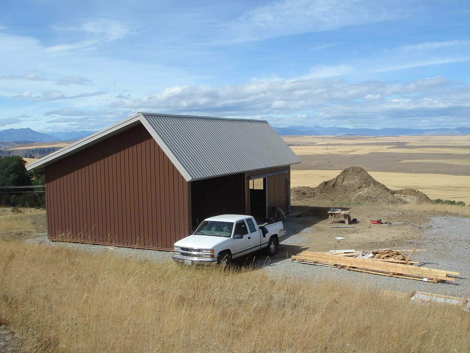 A pole barn style machine shed with metal siding in an open field