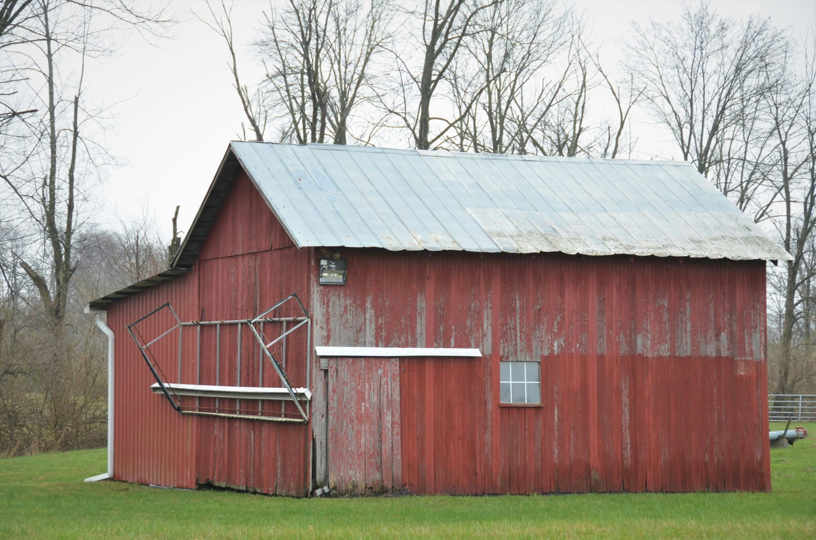 A finished pole barn with metal siding and a gable roof on an open rural lot