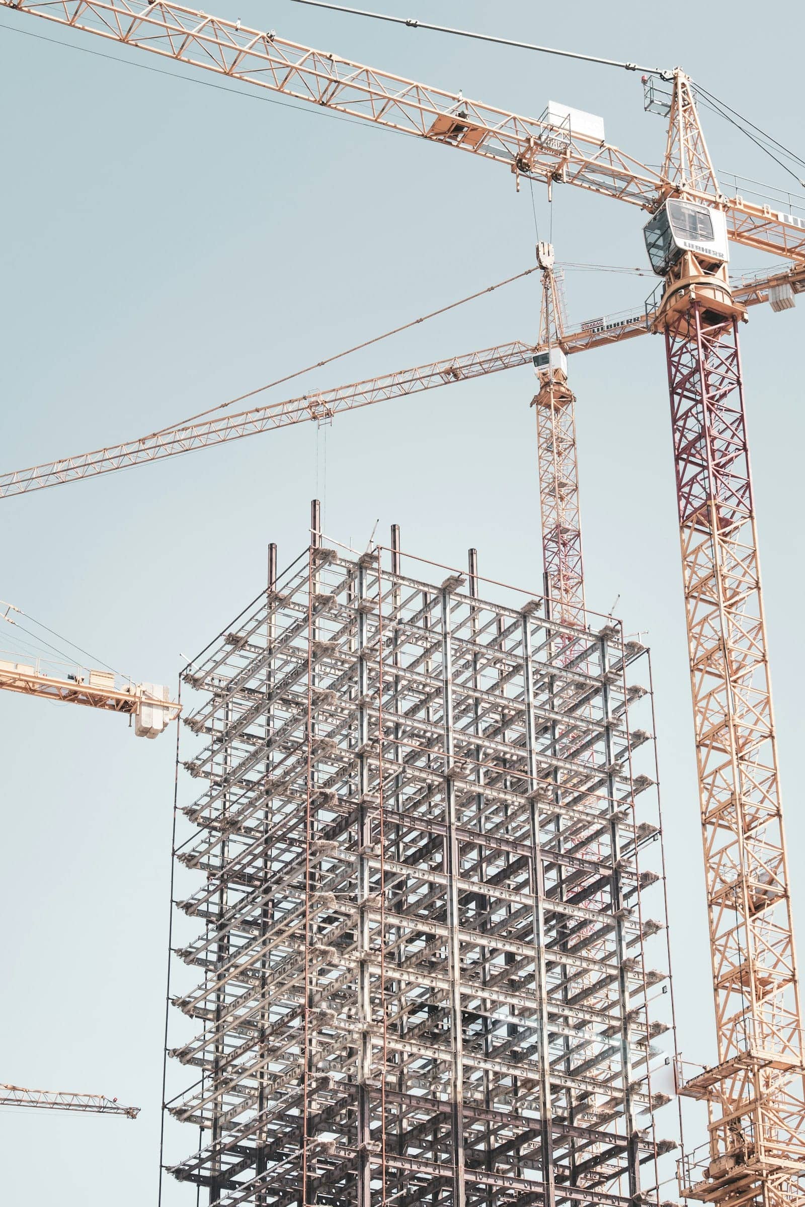 A gray steel building frame structure near a construction crane
