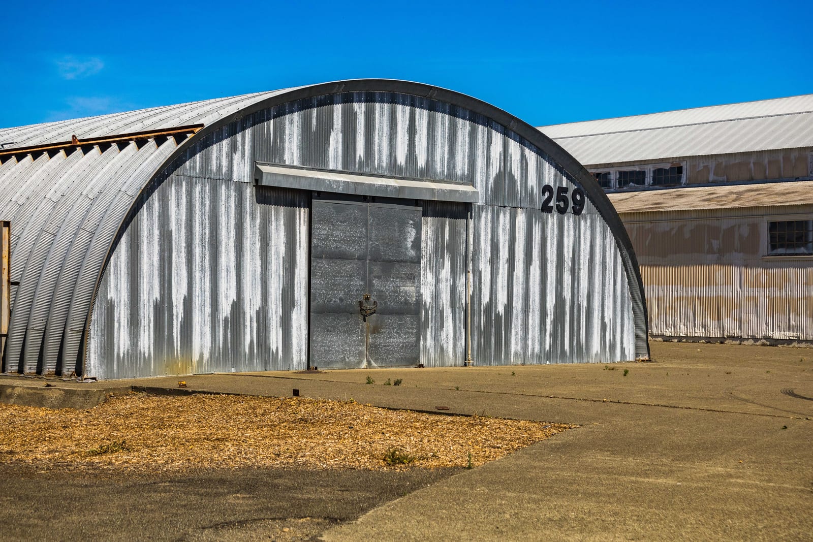 A white and gray arched quonset hut building under a clear blue sky