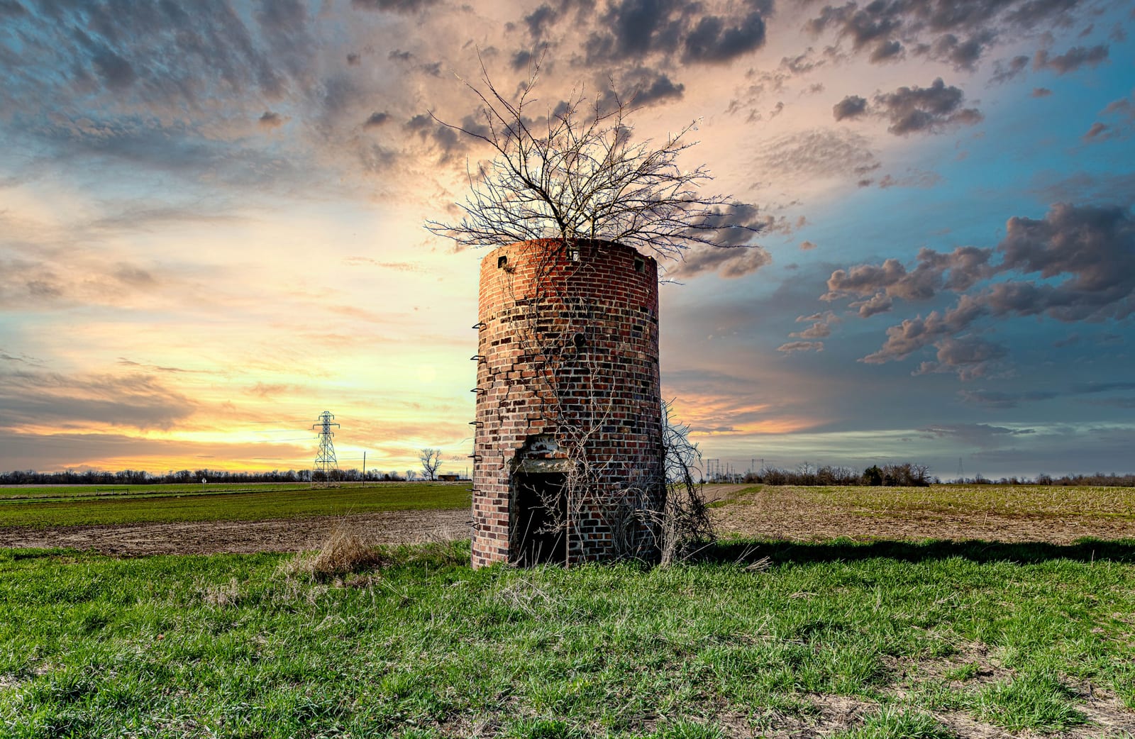 An older silo standing in a rural field at sunset